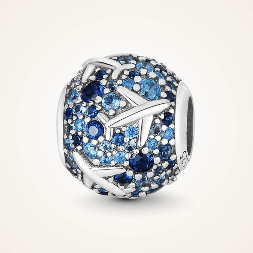 Sterling silver charm covered in light and dark blue stones with raised airplane motifs across the surface – ORÉYA