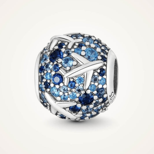 Sterling silver charm covered in light and dark blue stones with raised airplane motifs across the surface – ORÉYA