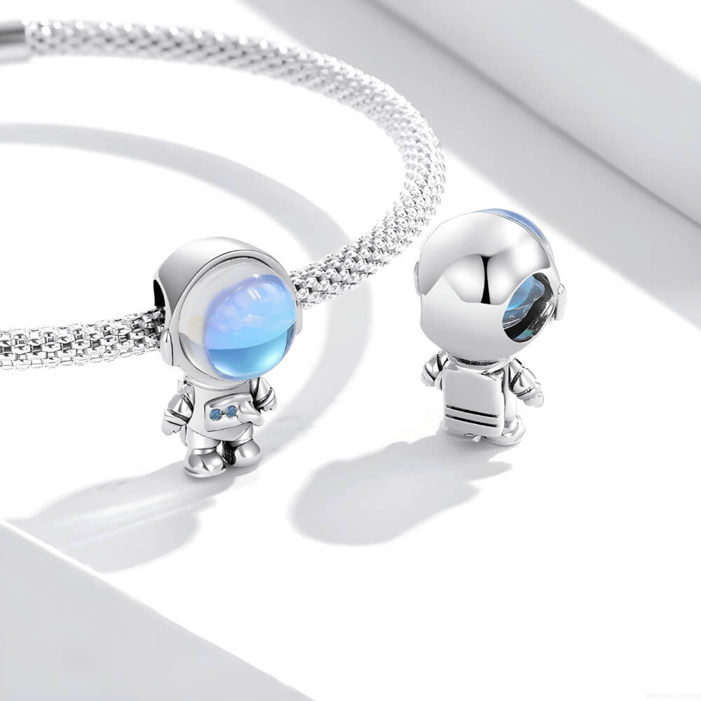 Sterling silver astronaut charm with a large iridescent glass helmet and small blue crystal details on the suit