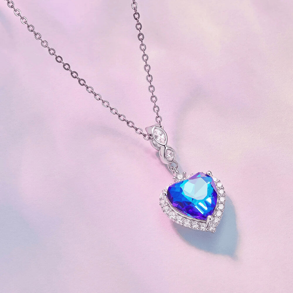 Sterling silver charm with a large faceted blue heart crystal framed by clear stones and a decorative bail set with clear marquise crystals