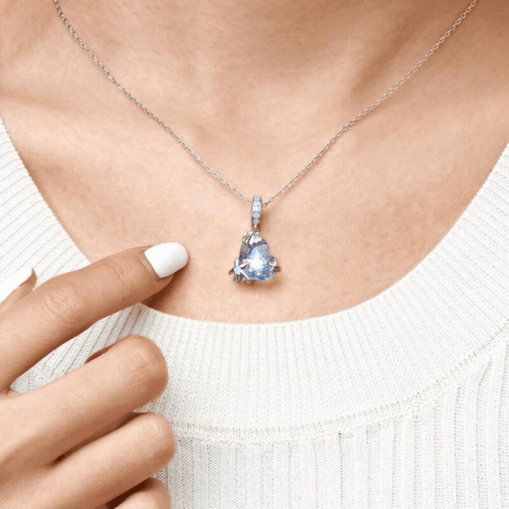 Sterling silver charm with a faceted blue heart crystal, silver seashell and starfish accents, and a bail set with light-blue stones