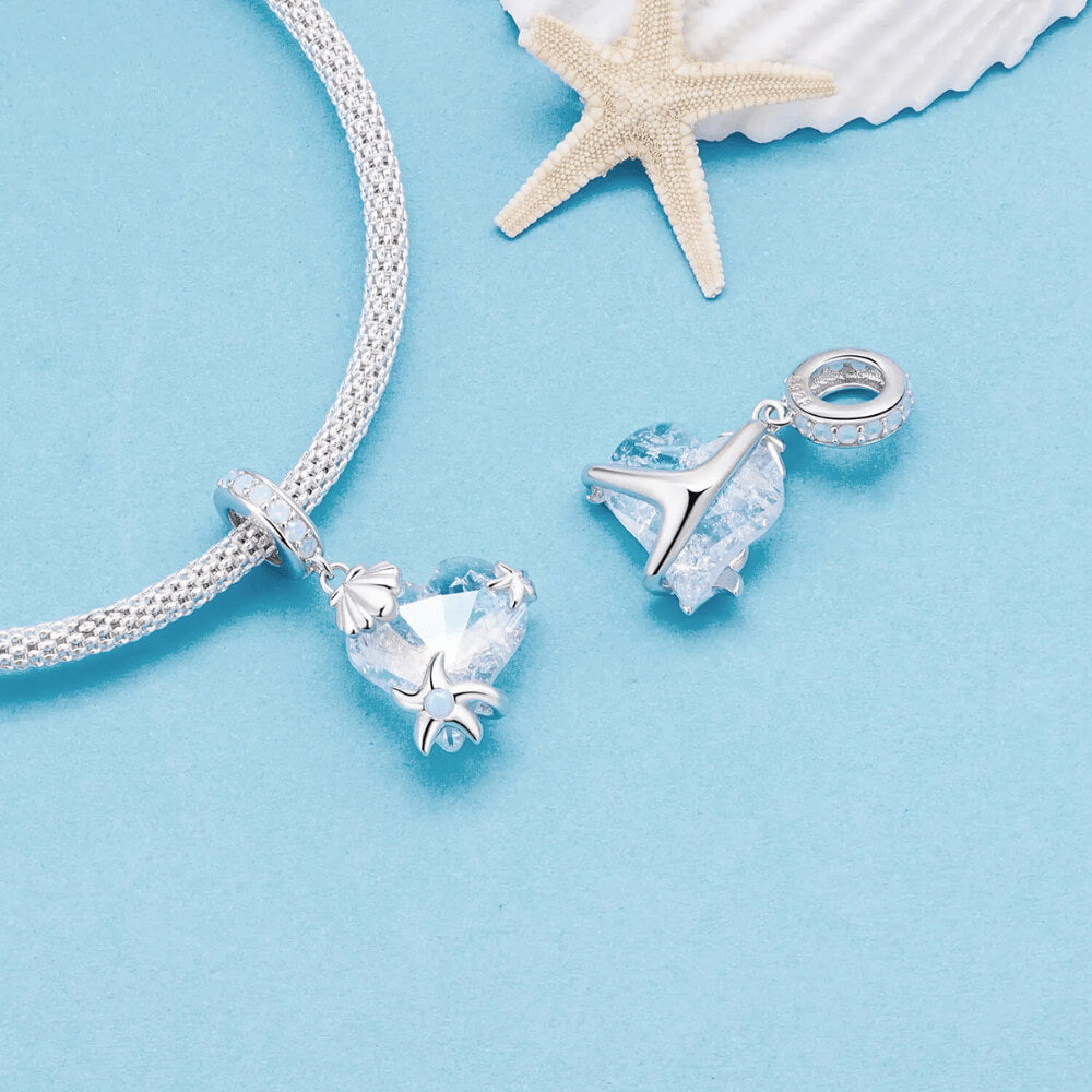 Sterling silver charm with a faceted blue heart crystal, silver seashell and starfish accents, and a bail set with light-blue stones 