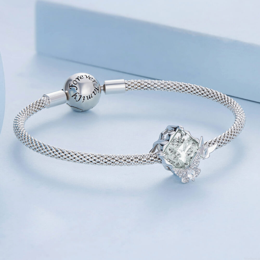 Sterling silver charm with a large pale green faceted stone and two crystal-studded silver butterflies on the front 