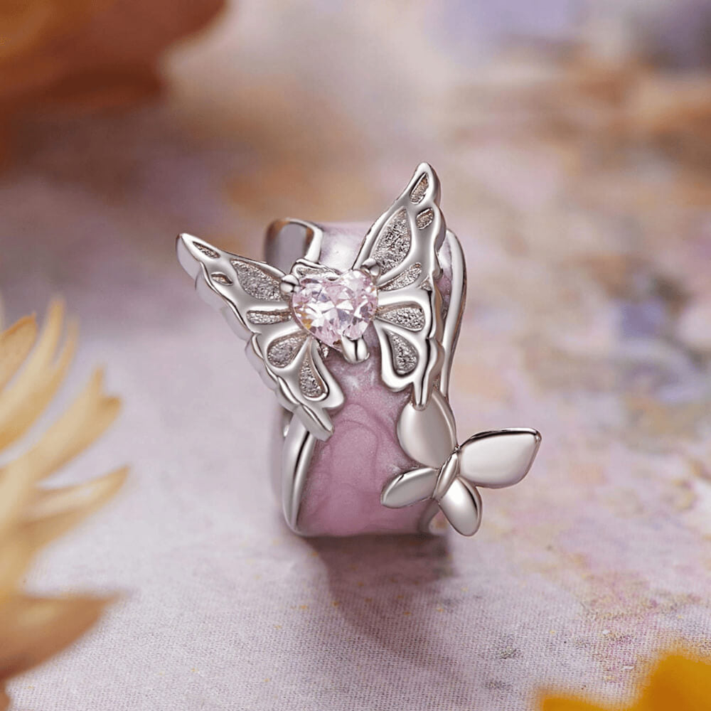 Sterling silver charm with a pale pink enamel background, a silver butterfly with a pink heart-shaped stone, and an additional silver flower detail 