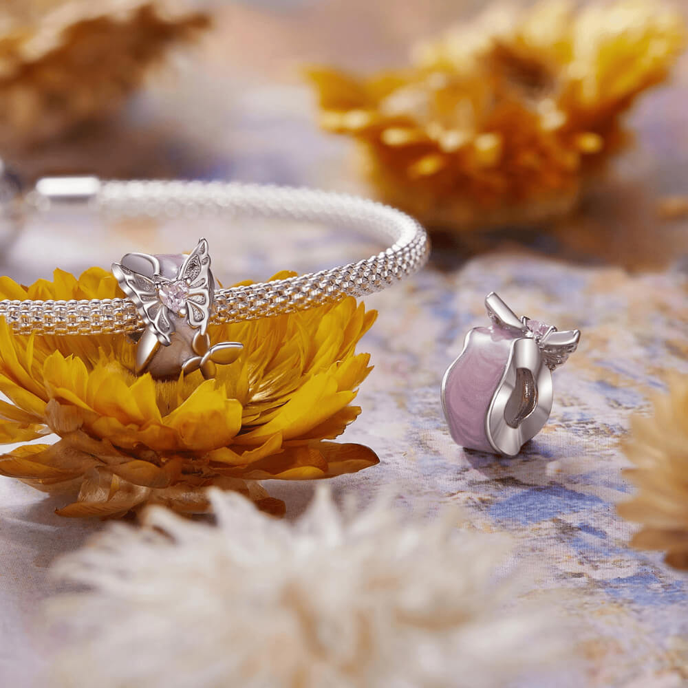 Sterling silver charm with a pale pink enamel background, a silver butterfly with a pink heart-shaped stone, and an additional silver flower detail 