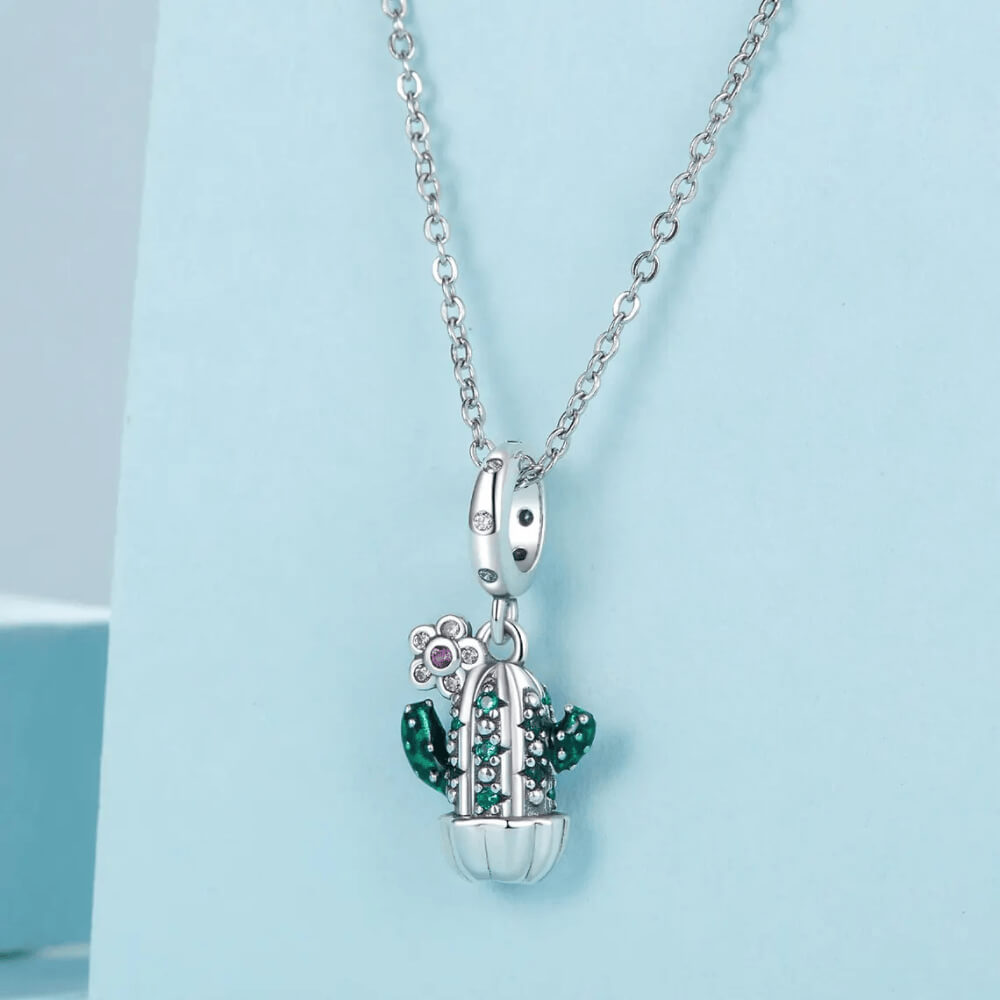 Sterling silver cactus charm with green enamel arms, green gemstones, and a small flower pendant with a pink crystal 