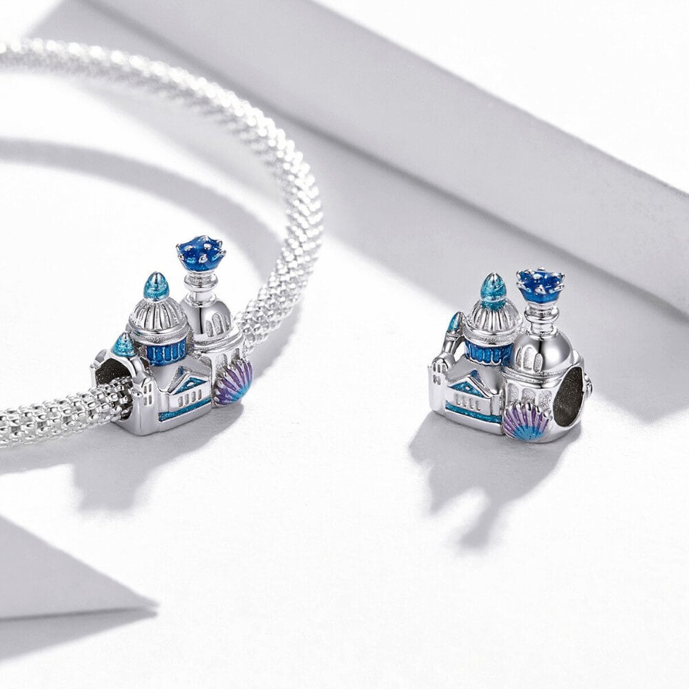 Sterling silver castle charm with blue enamel domes, glitter details, and shell accent.