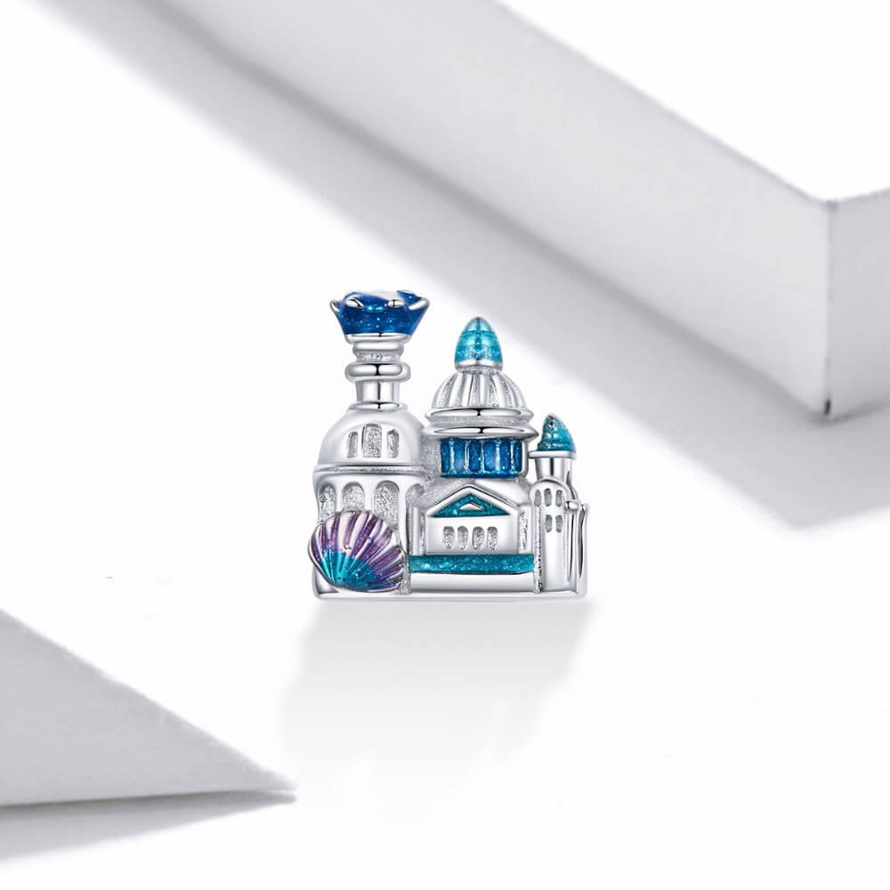 Sterling silver castle charm with blue enamel domes, glitter details, and shell accent.