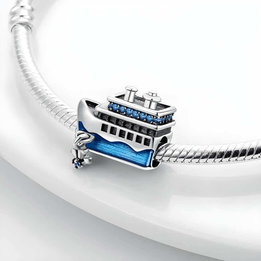 Sterling silver cruise-ship charm with blue enamel waves, blue crystal details on the upper deck, and a dangling anchor with a blue stone