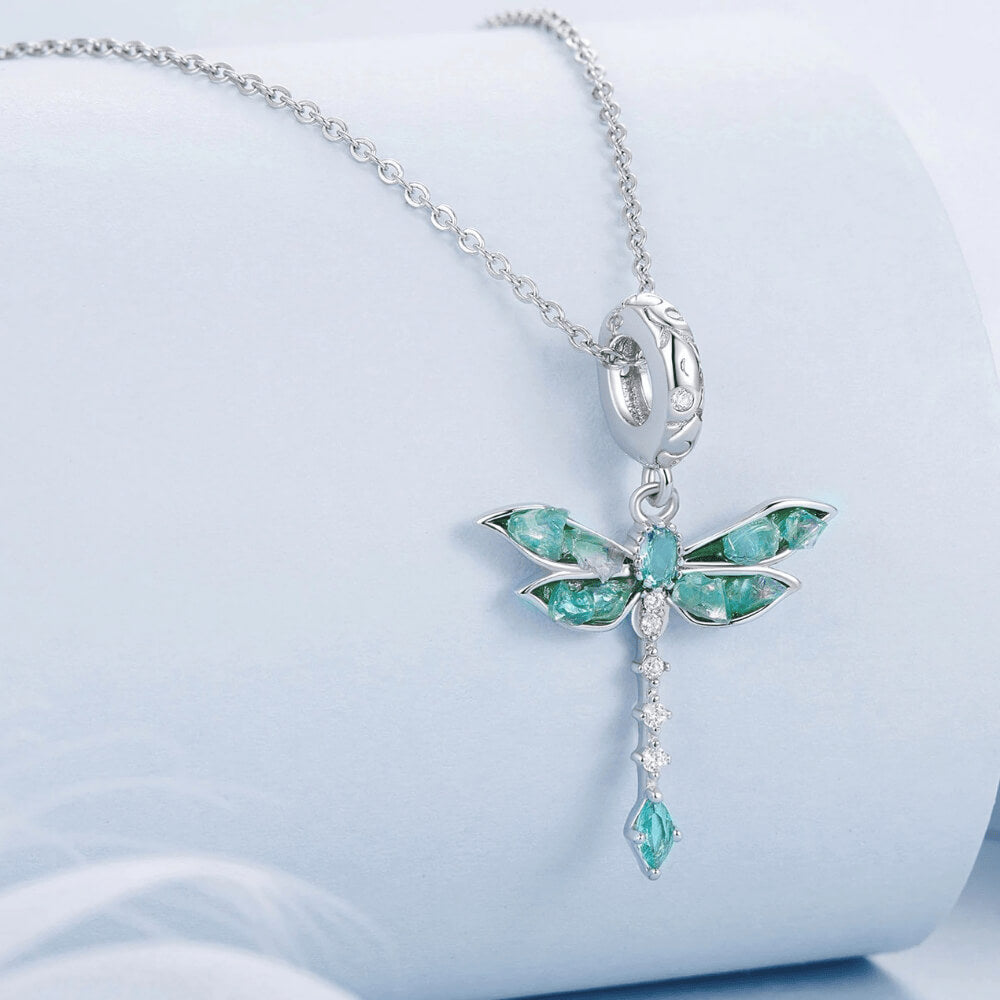 Sterling silver dragonfly charm with blue-green iridescent enamel wings, sparkling clear stones, and a teardrop blue crystal tail 