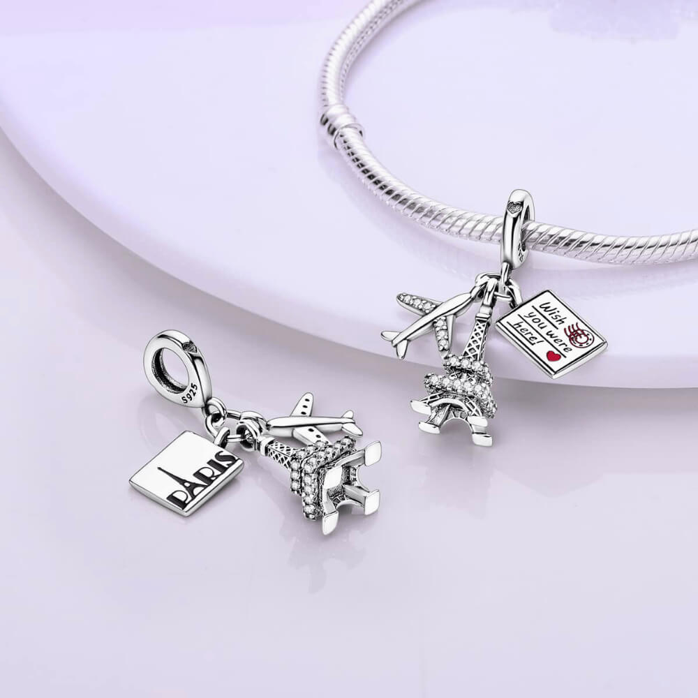 Sterling silver charm with a crystal-studded Eiffel Tower, a small airplane with clear stones, and an engraved postcard
