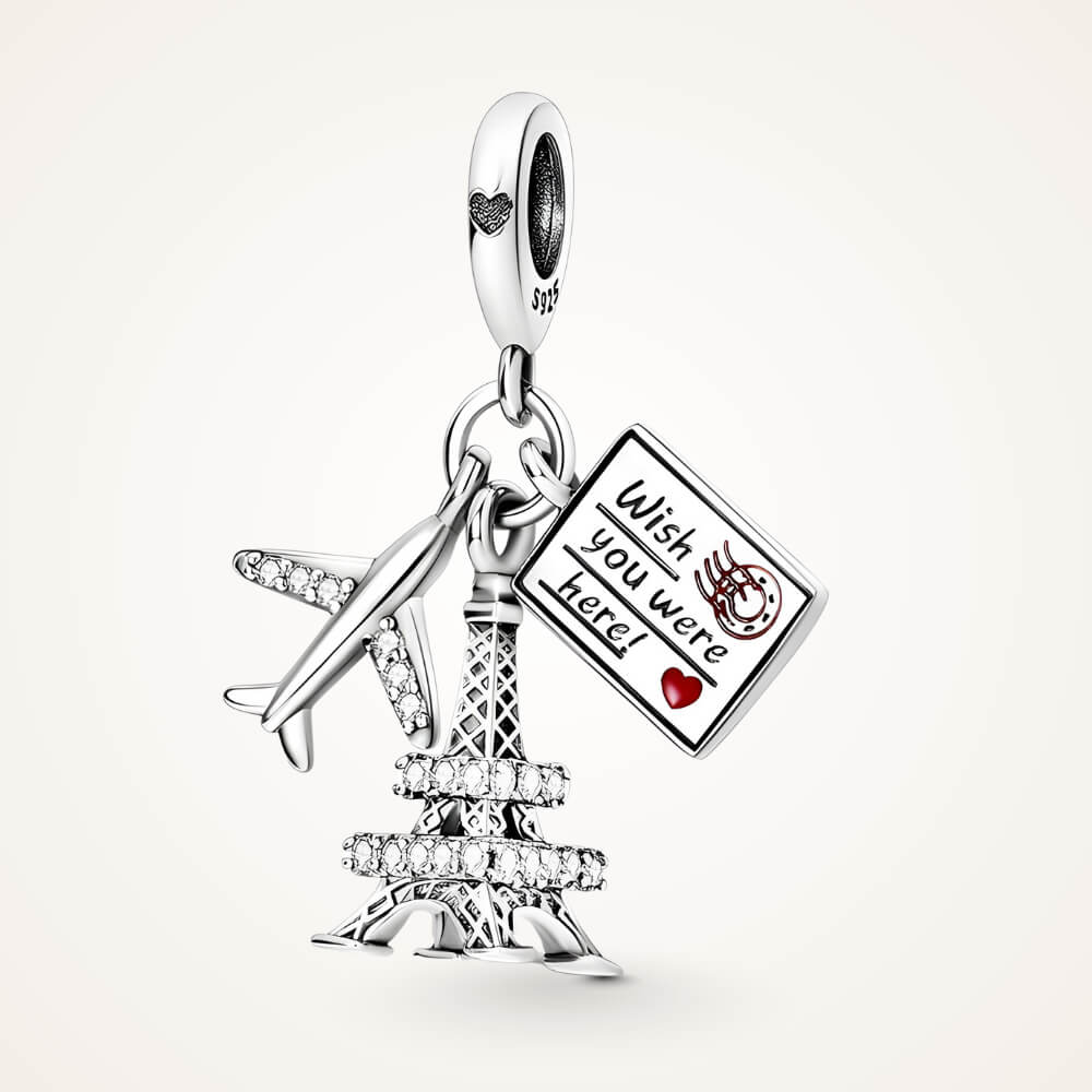 Sterling silver charm with a crystal-studded Eiffel Tower, a small airplane with clear stones, and an engraved postcard – ORÉYA.