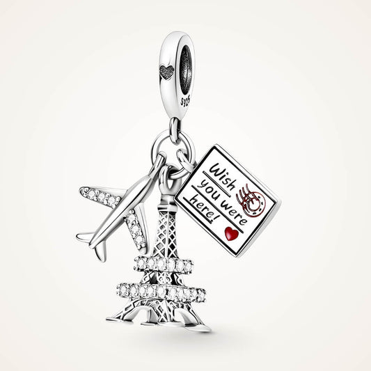 Sterling silver charm with a crystal-studded Eiffel Tower, a small airplane with clear stones, and an engraved postcard – ORÉYA.