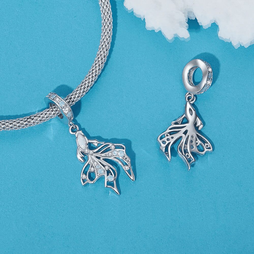 Sterling silver fish charm with opal-like stone and blue gemstone accents.