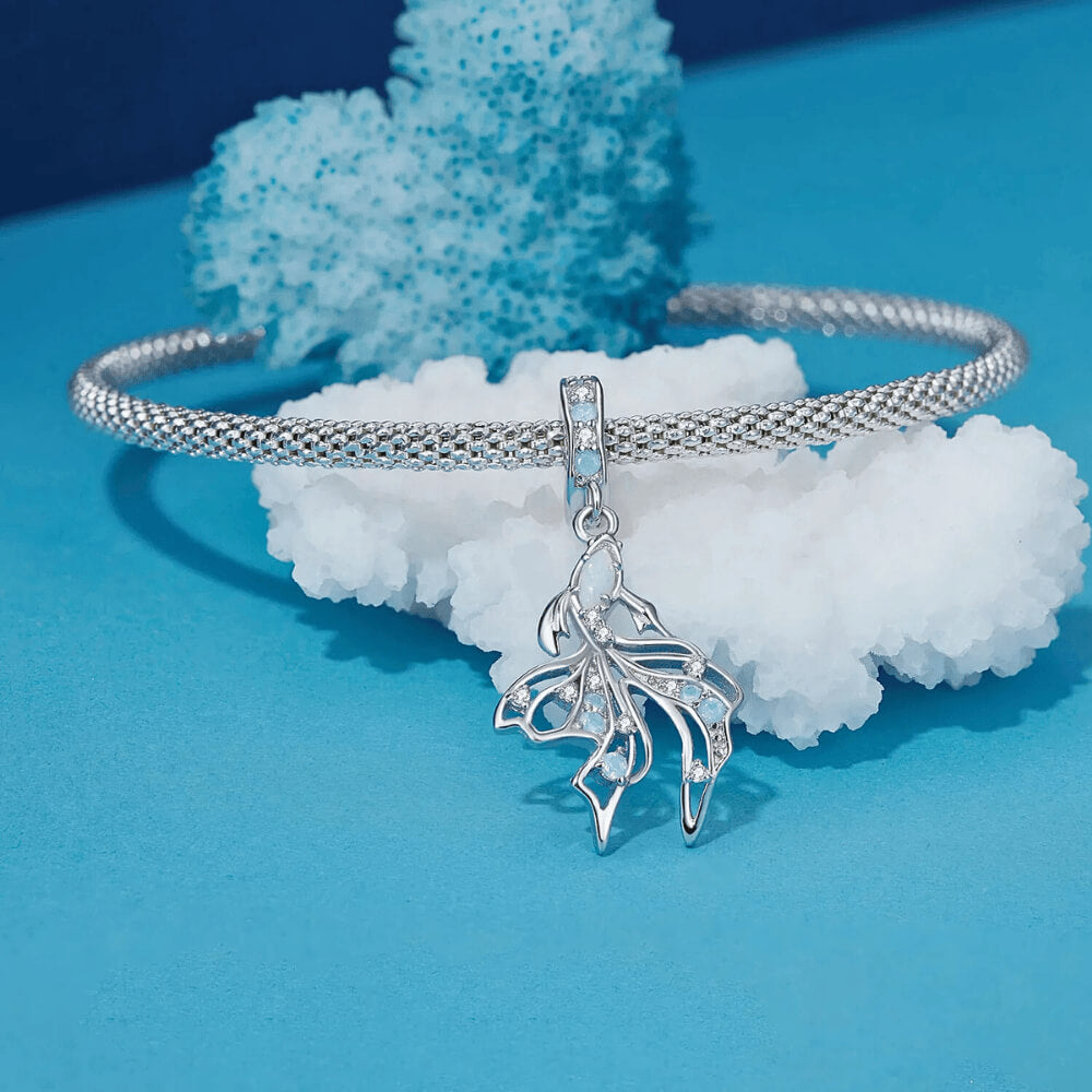 Sterling silver fish charm with opal-like stone and blue gemstone accents.