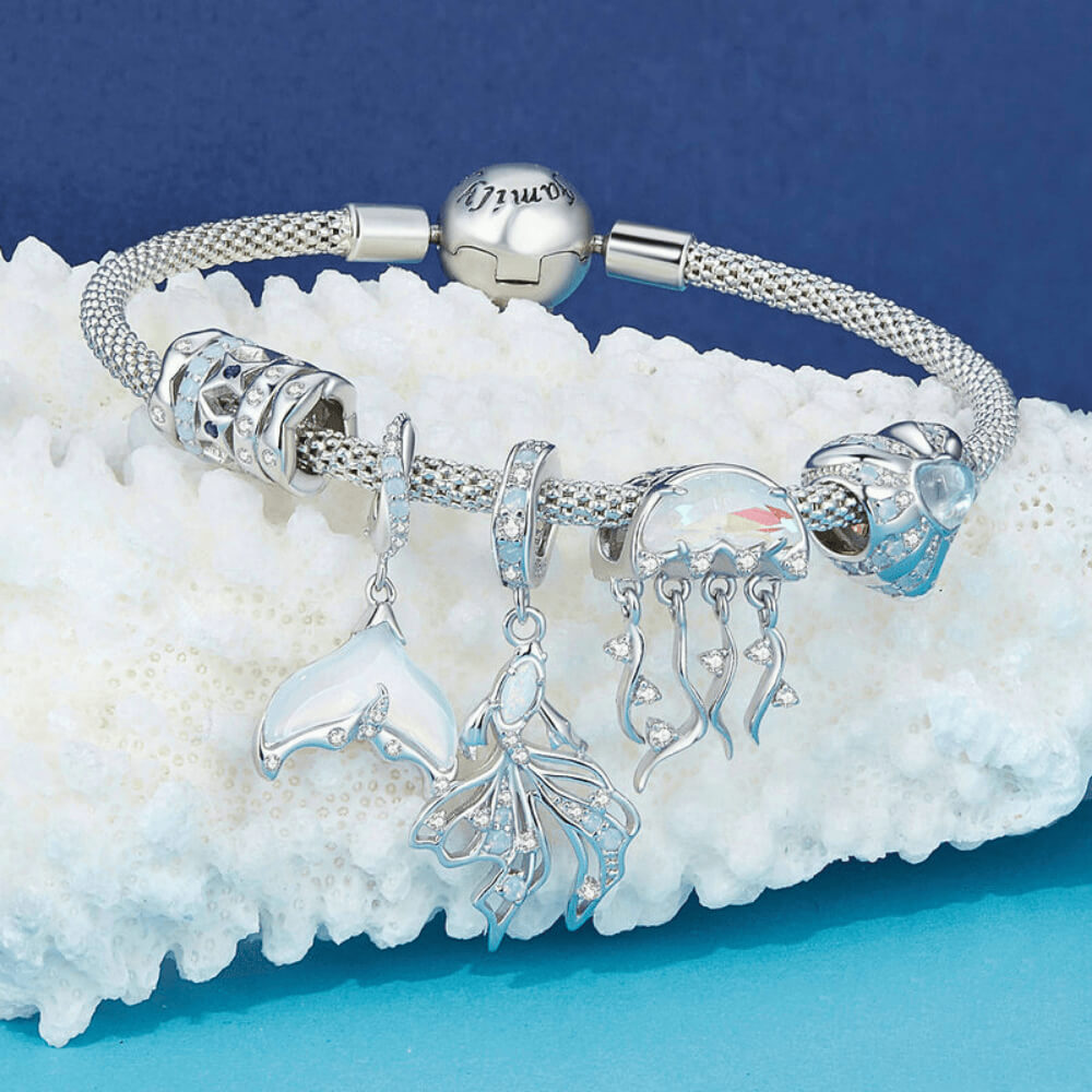 Sterling silver fish charm with opal-like stone and blue gemstone accents.