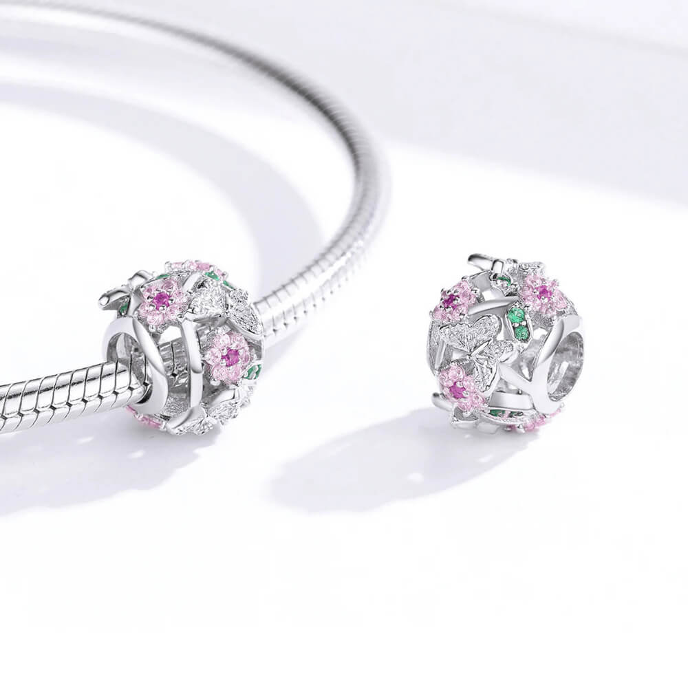 Sterling silver openwork charm with pink crystal flowers, green crystal leaves, and silver butterflies with clear stones 