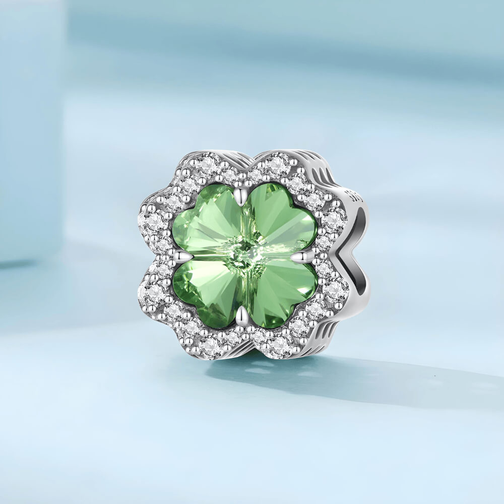 Sterling silver charm with a large green four-petal faceted stone framed by clear crystals