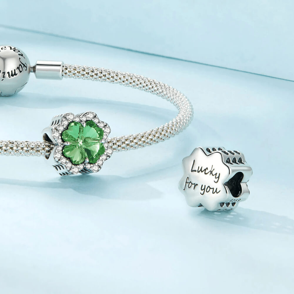 Sterling silver charm with a large green four-petal faceted stone framed by clear crystals