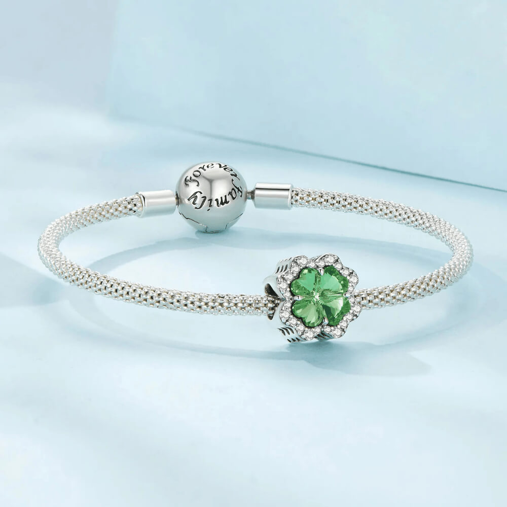 Sterling silver charm with a large green four-petal faceted stone framed by clear crystals