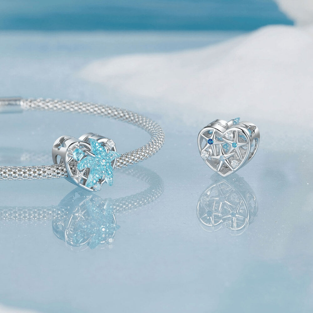 Sterling silver heart-shaped charm with a large blue crystal starfish, light-blue and clear stones, and an openwork background 