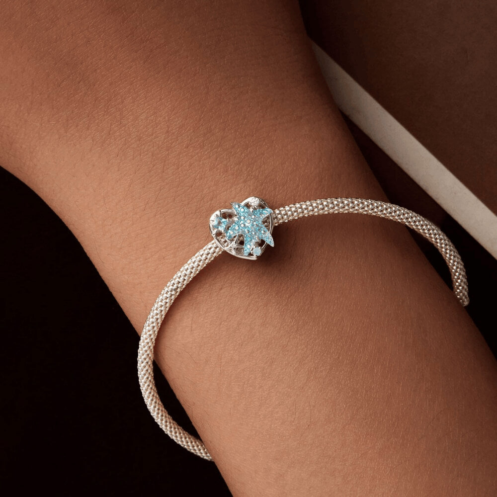 Sterling silver heart-shaped charm with a large blue crystal starfish, light-blue and clear stones, and an openwork background 