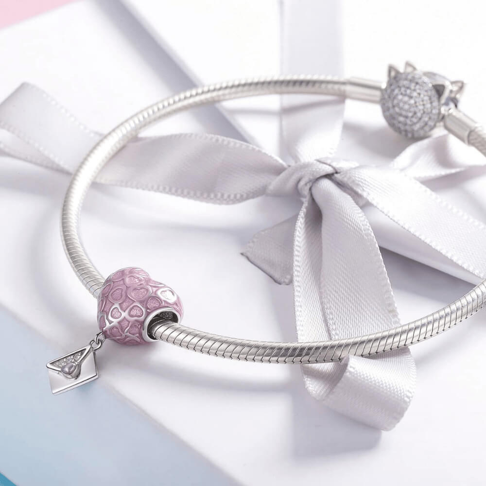 Sterling silver heart charm with pink enamel heart patterns and a dangling envelope accented with a small pink heart