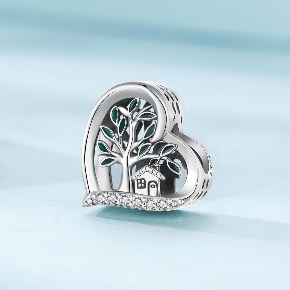 Sterling silver heart-shaped charm with a green-enamel tree, small house detail, and a row of clear crystals along the bottom 