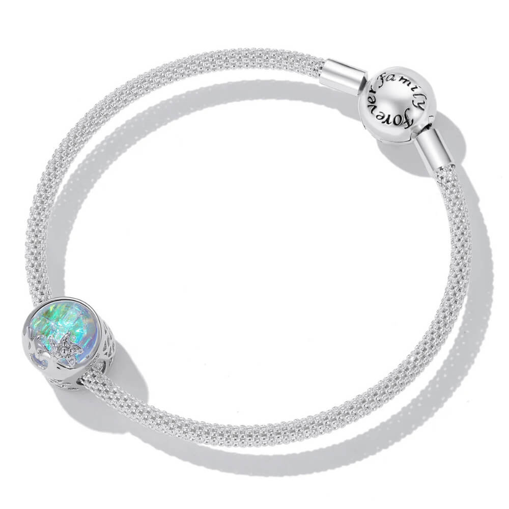 Sterling silver charm with an iridescent round glass center, featuring silver starfish and wave details on the surface 