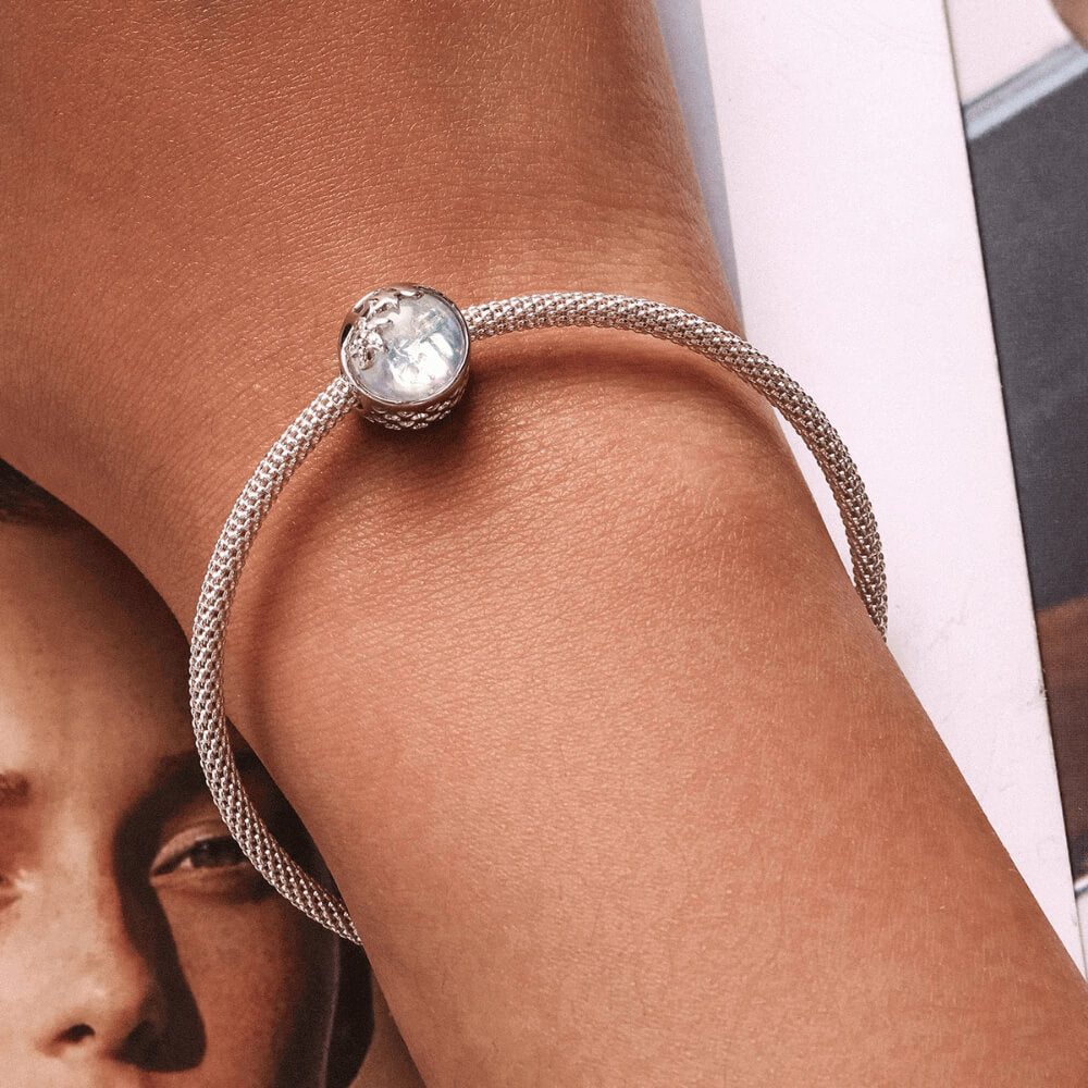 Sterling silver charm with an iridescent round glass center, featuring silver starfish and wave details on the surface 
