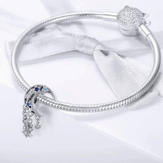 Sterling silver crescent moon charm with clear, dark blue, and light blue stones, featuring three dangling star and circle crystal accents