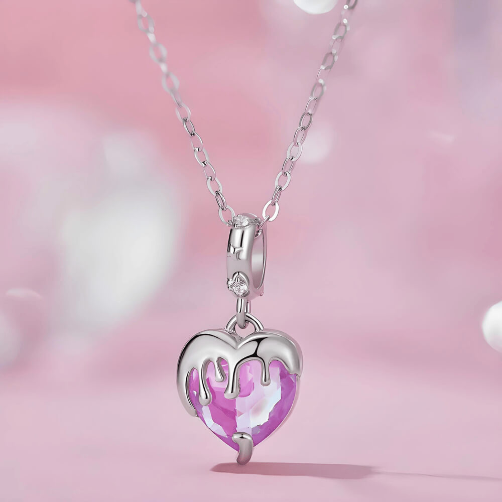 Sterling silver charm with a faceted pink heart crystal covered by a silver melting-drip design and a bail set with small clear stones