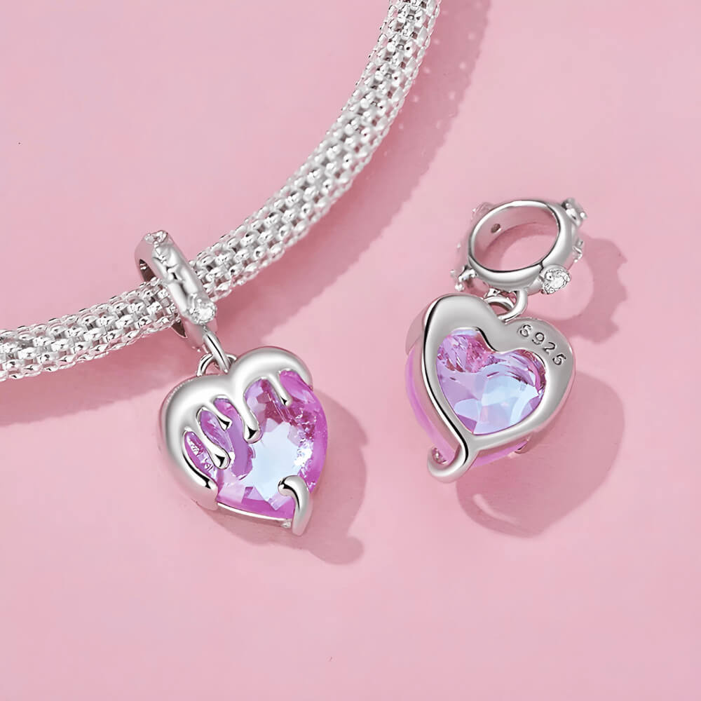 Sterling silver charm with a faceted pink heart crystal covered by a silver melting-drip design and a bail set with small clear stones