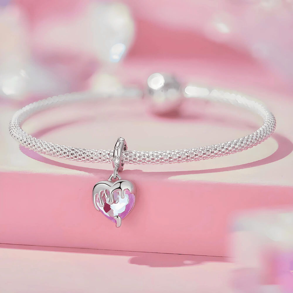 Sterling silver charm with a faceted pink heart crystal covered by a silver melting-drip design and a bail set with small clear stones