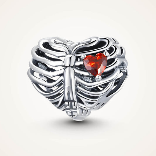 Sterling silver ribcage-shaped charm with an openwork design and a small red heart-shaped crystal inside – ORÉYA