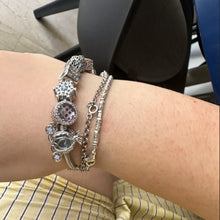 Sterling silver snowflake charm with detailed openwork design and light blue gemstones.