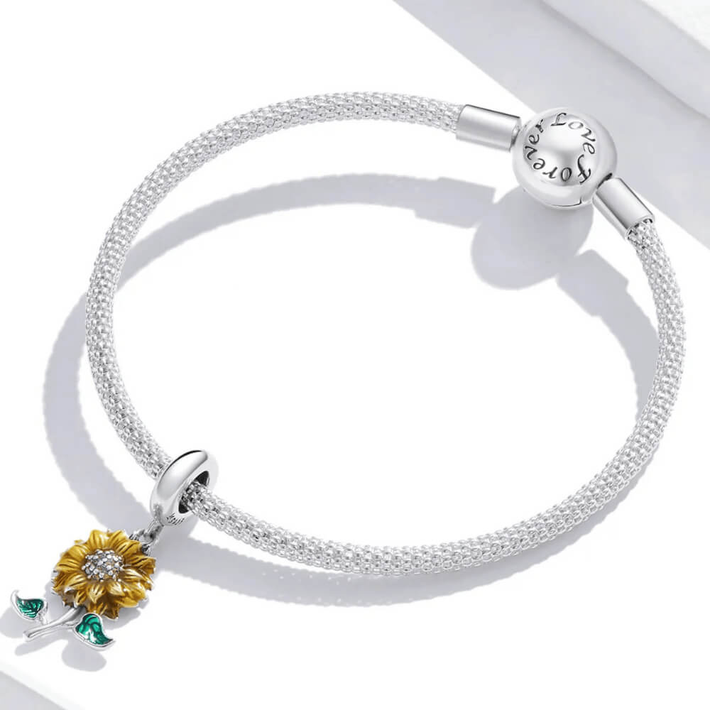 Sterling silver sunflower charm with yellow enamel petals, a crystal-studded center, and two green enamel leaves 