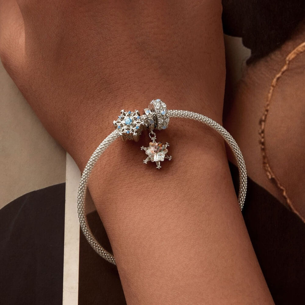 Sterling silver snowflake charm with iridescent crystal and blue accents.
