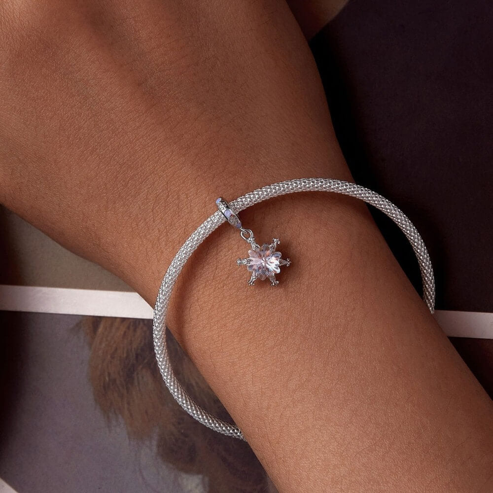 Sterling silver snowflake charm with iridescent crystal and blue accents.