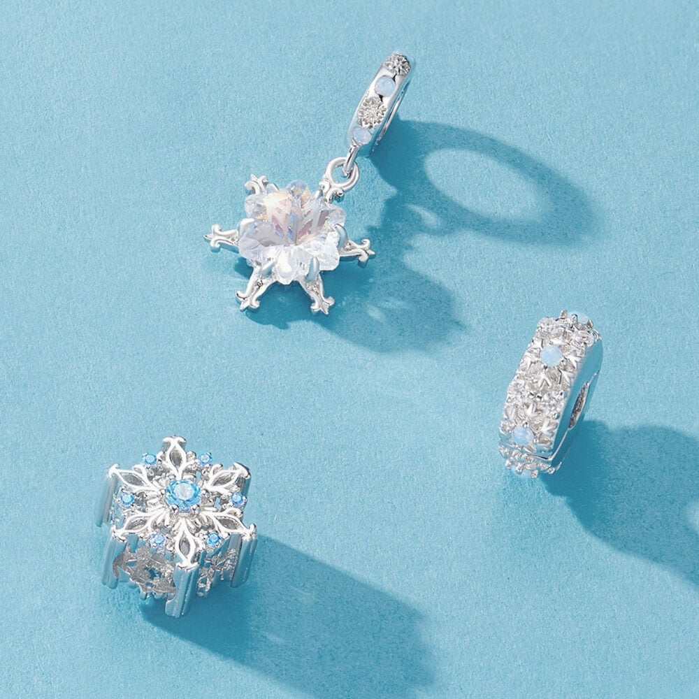 Sterling silver snowflake charm with iridescent crystal and blue accents.