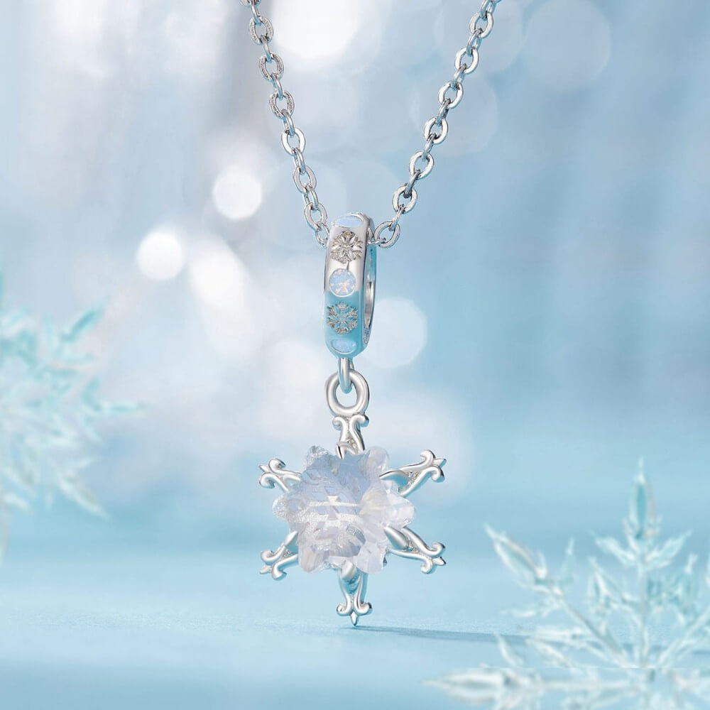 Sterling silver snowflake charm with iridescent crystal and blue accents.