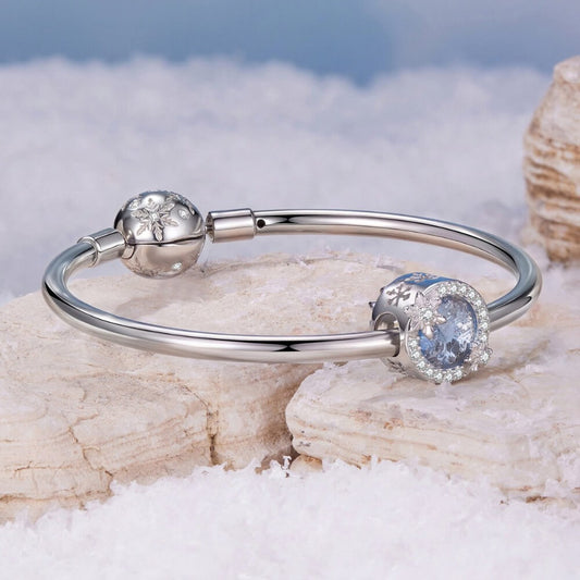 Sterling silver snowflake charm with icy crystal center and pavé details.