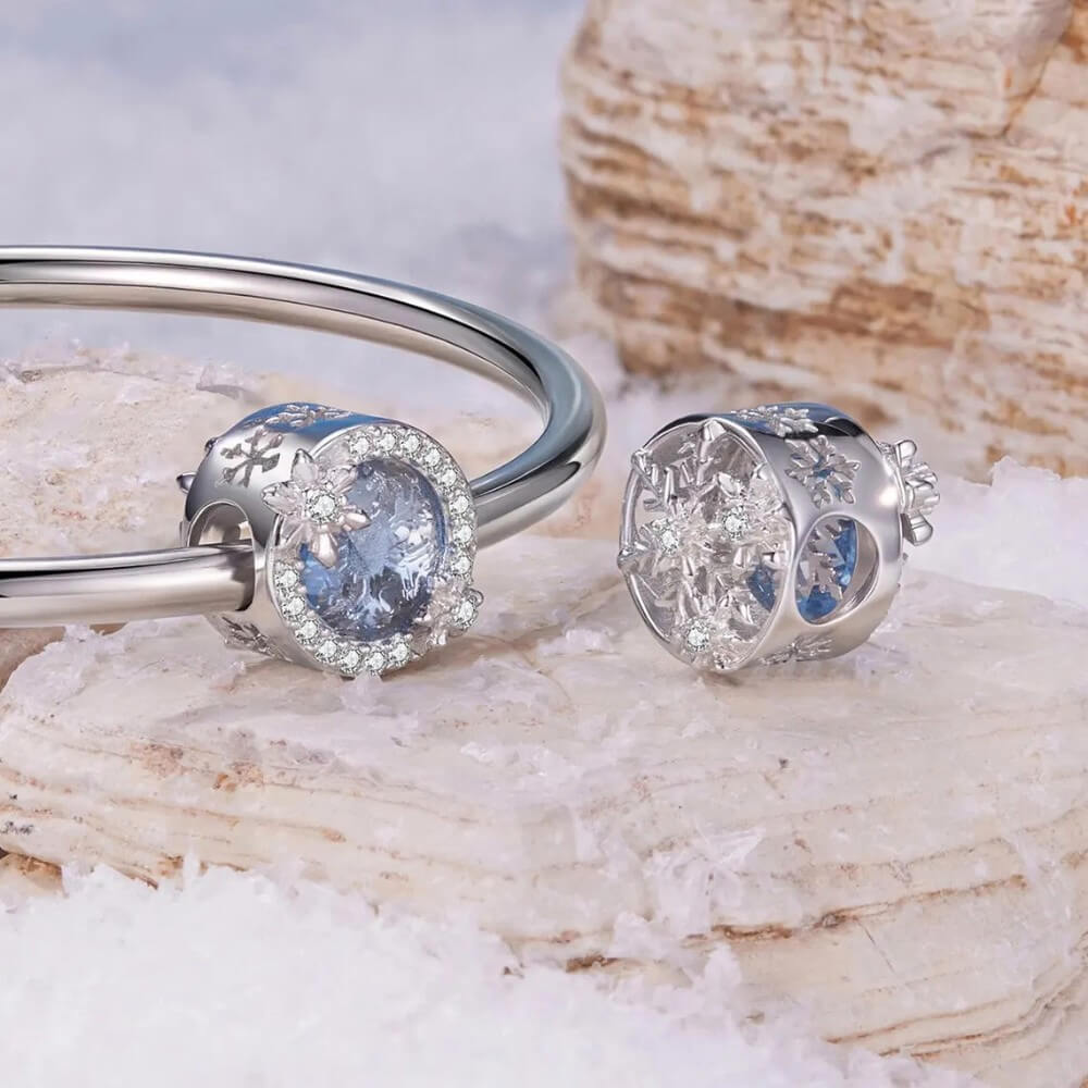 Sterling silver snowflake charm with icy crystal center and pavé details.