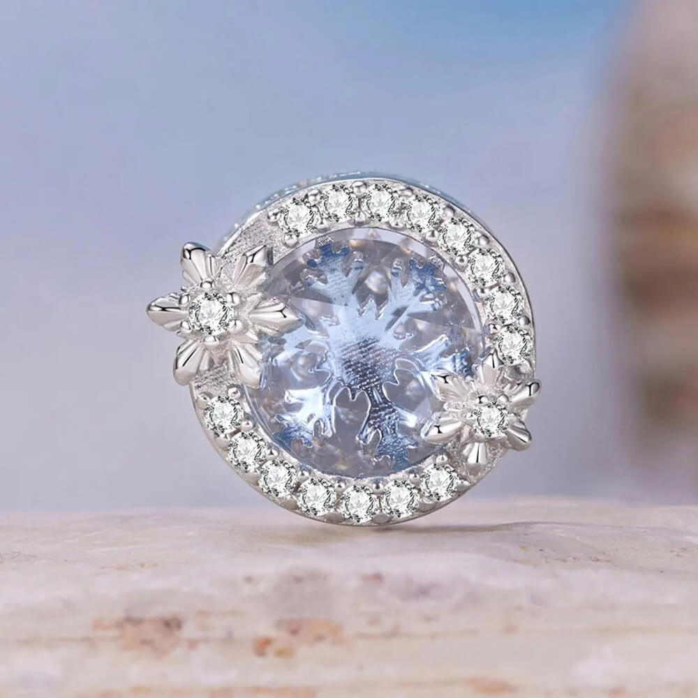 Sterling silver snowflake charm with icy crystal center and pavé details.