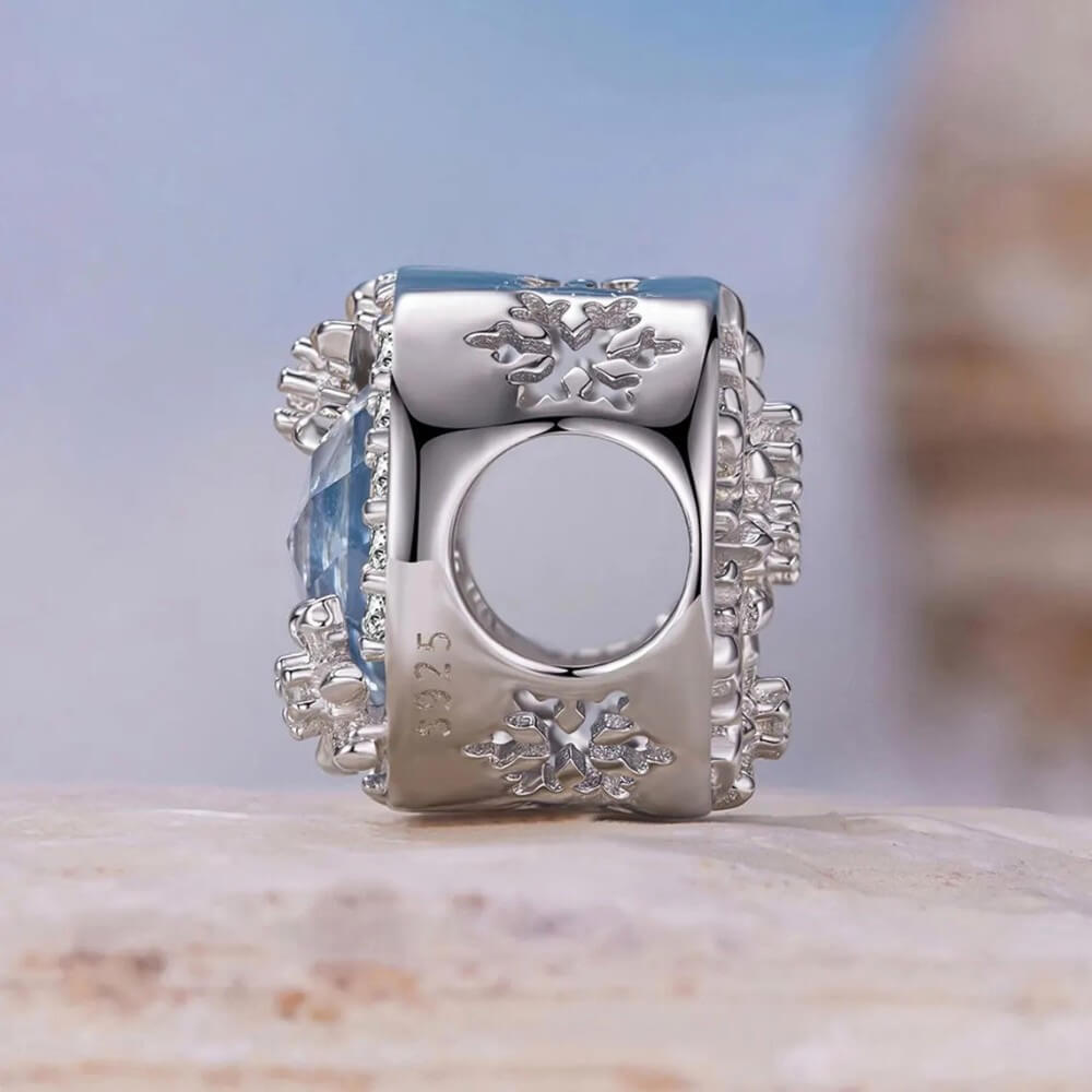 Sterling silver snowflake charm with icy crystal center and pavé details.