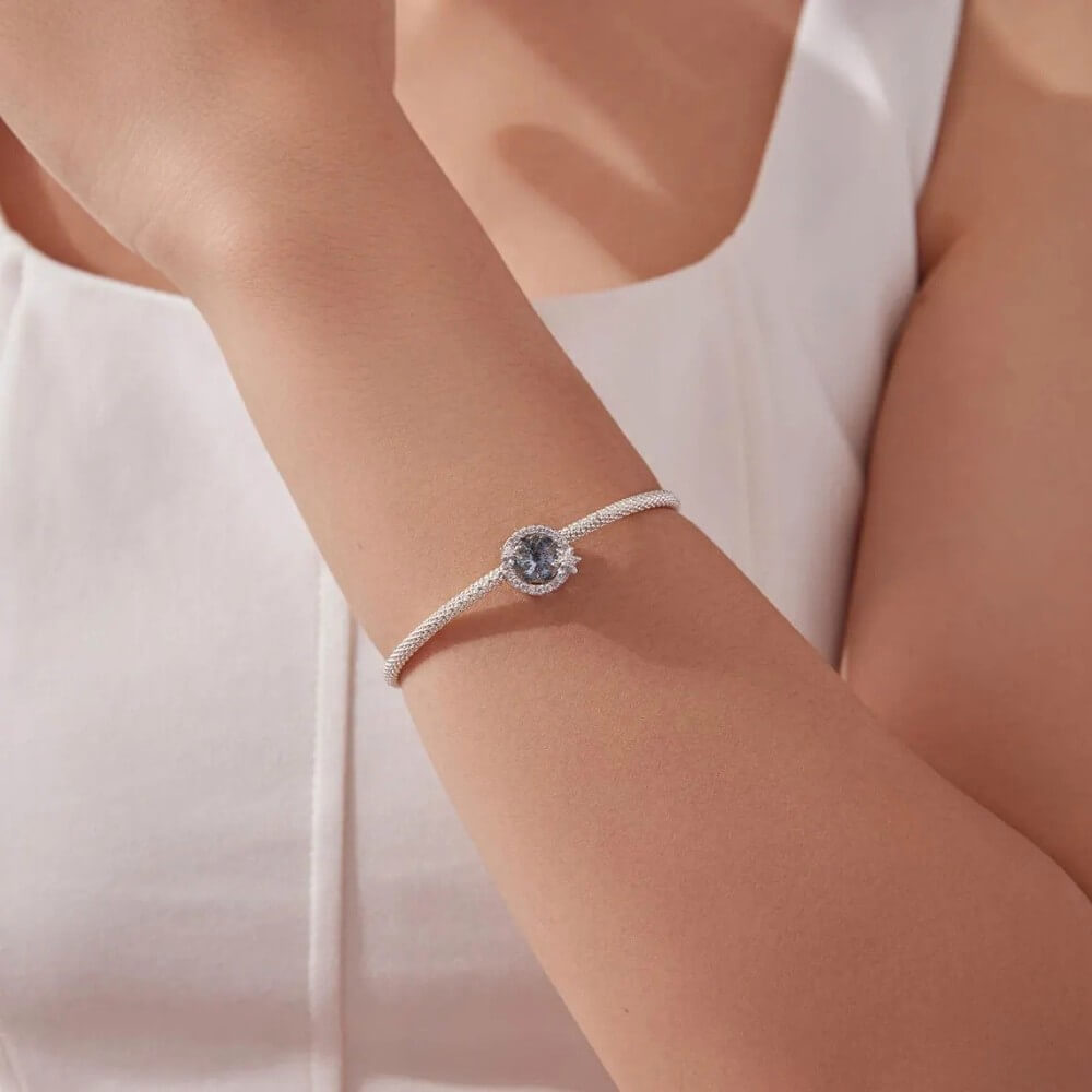 Sterling silver snowflake charm with icy crystal center and pavé details.