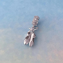 Sterling silver ballet shoes charm with delicate bow and soft pink opalescent detail.