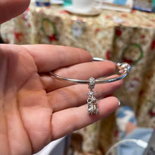 Sterling silver ballet shoes charm with delicate bow and soft pink opalescent detail.