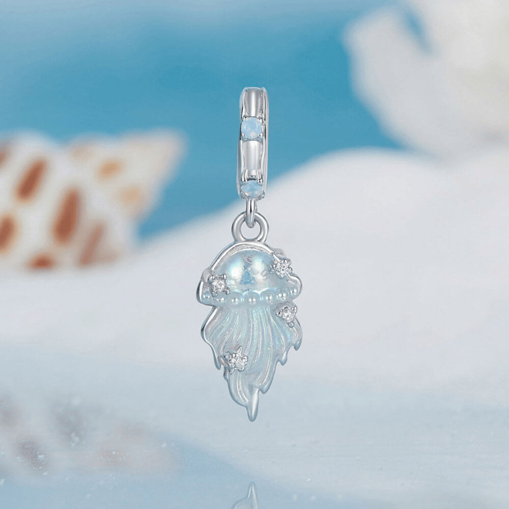 Sterling silver jellyfish dangle charm with iridescent enamel body, flowing tentacle design, and small clear gemstones on the bail and charm 