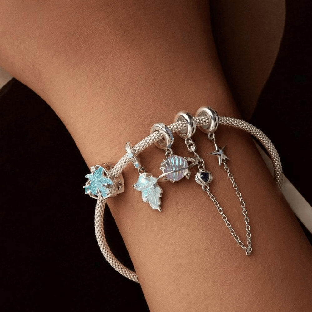Sterling silver jellyfish dangle charm with iridescent enamel body, flowing tentacle design, and small clear gemstones on the bail and charm